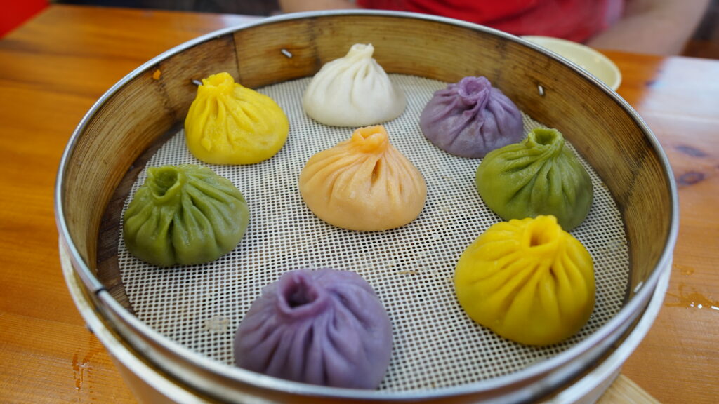 Assorted colourful dumplings in a metal tin with a variety of flavors and fillings.