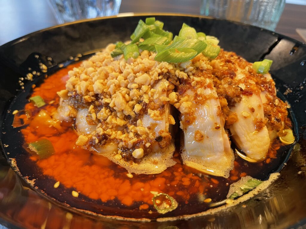 Chicken meal on a plate with chilli oil and two glass of water