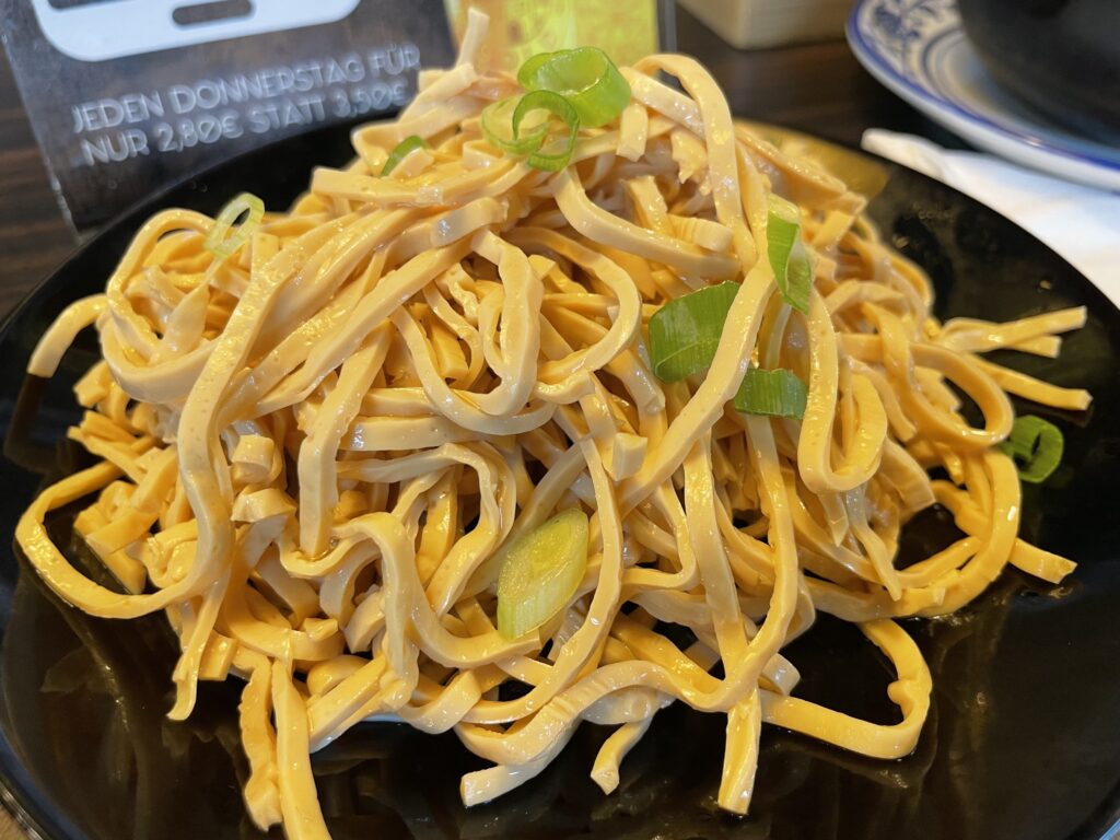 A plate of shredded tofu topped with fresh spring onions