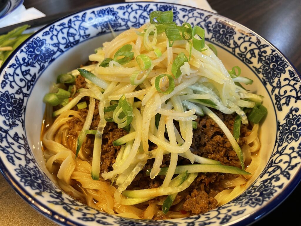 A bowl of noodles with meat and vegetables, a delicious and colorful meal