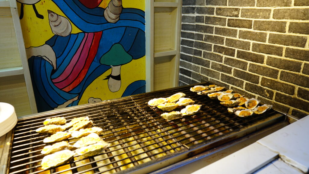 A grill with oysters sizzling on it at a street food stall in Wuhan.