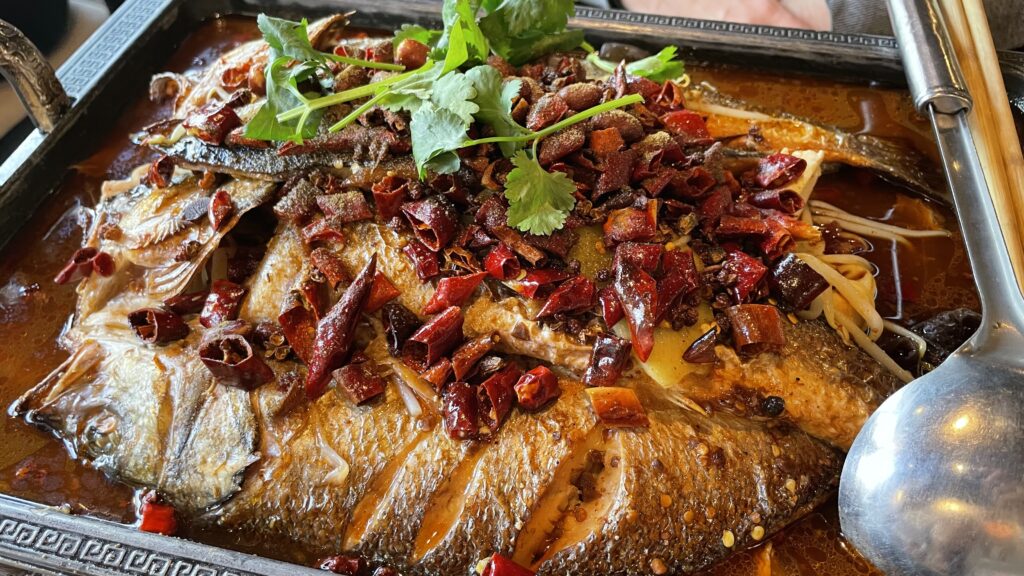 A large Sichuan grill fish on a tray with a spoon in a restaurant in Frankfurt