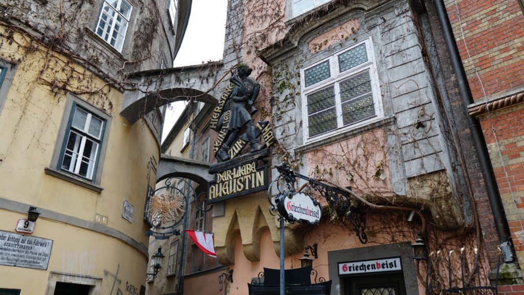 Scenic view of a charming narrow street in Vienna with various signs and sculptures.