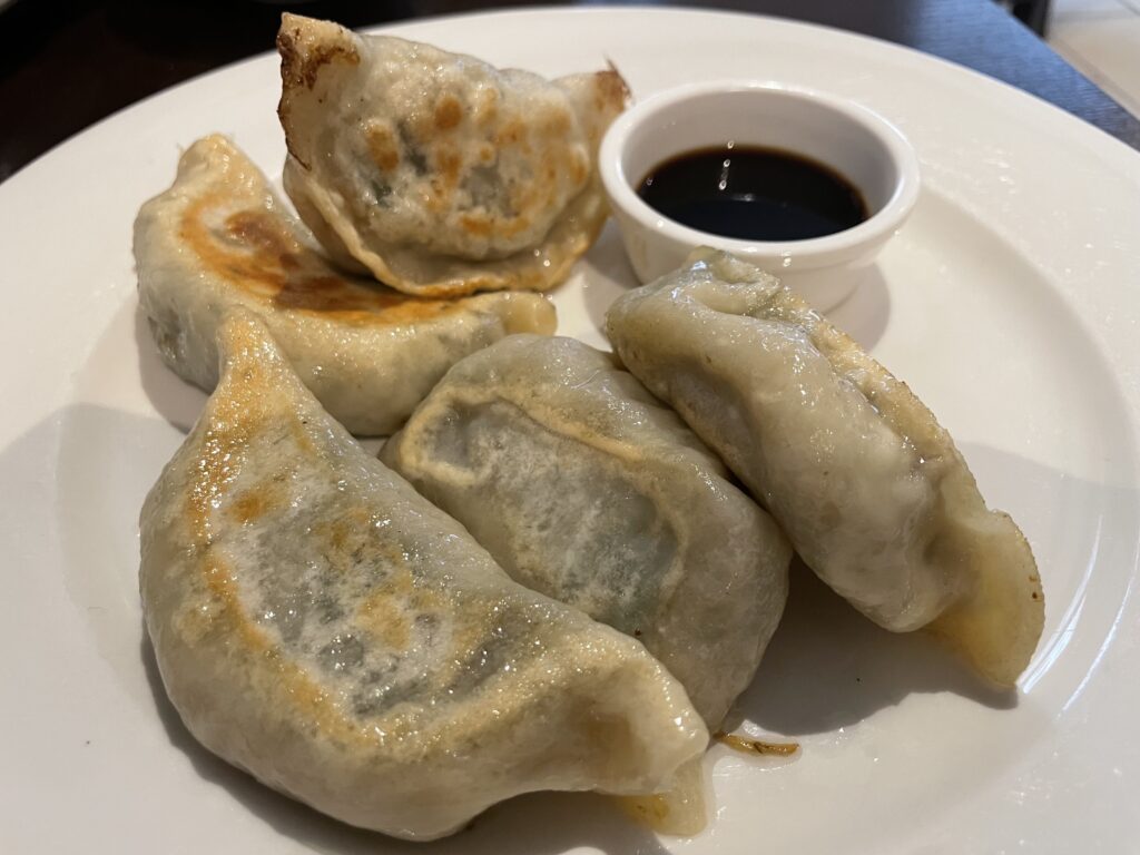 A plate of fried Chinese chive pockets served with vinegar, a delicious Asian culinary delight.