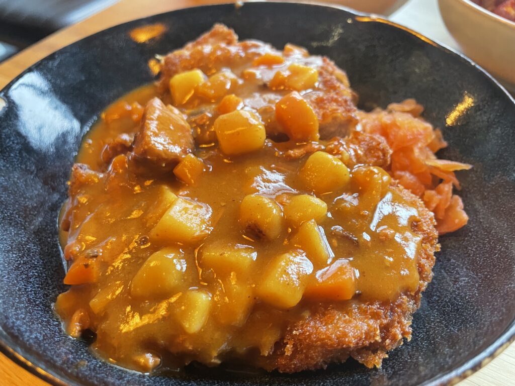 A bowl of pork cutlet with Japanese curry and vegetables served at a Japanese donburi restaurant in Frankfurt