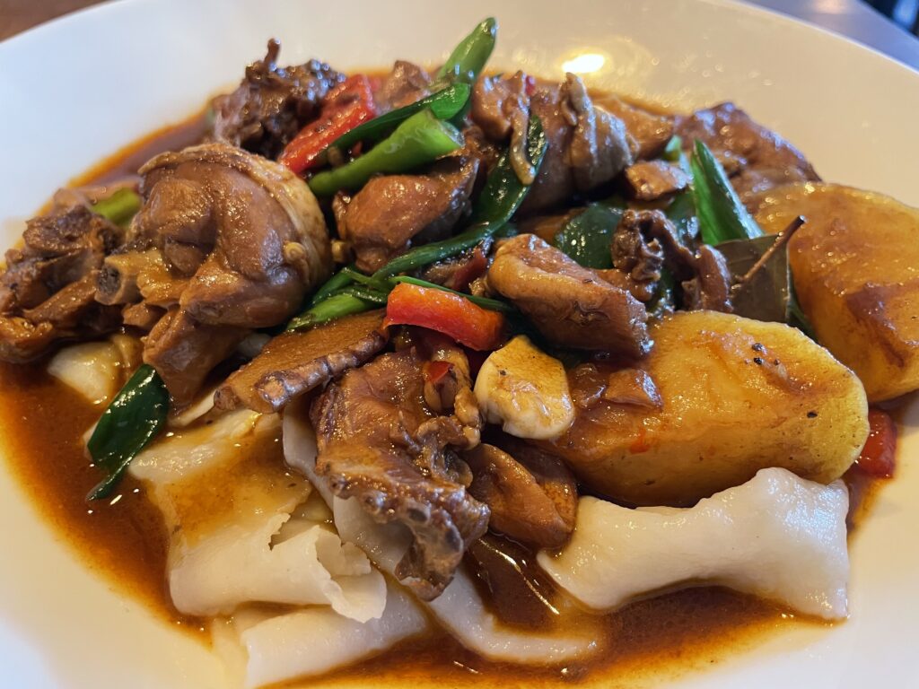 Plate of Dapanji or Tohu Kordak, a Xinjiang dish with chicken, noodles, potatoes and vegetables - Uyghur Cuisine at Taklamakan Restaurant in Munich